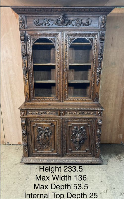 A two-tier dark oak cabinet featuring arched glazed top doors, carved scroll motifs, and lower doors with relief carvings of game birds. View XI