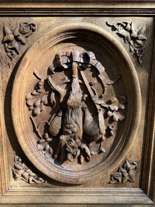A two-piece bleached oak hunting cabinet featuring hand-carved relief panels of game birds, glazed upper doors, and a decorative mask pediment. View VI