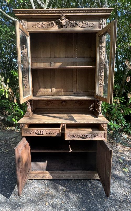 A two-piece bleached oak hunting cabinet featuring hand-carved relief panels of game birds, glazed upper doors, and a decorative mask pediment. View XI