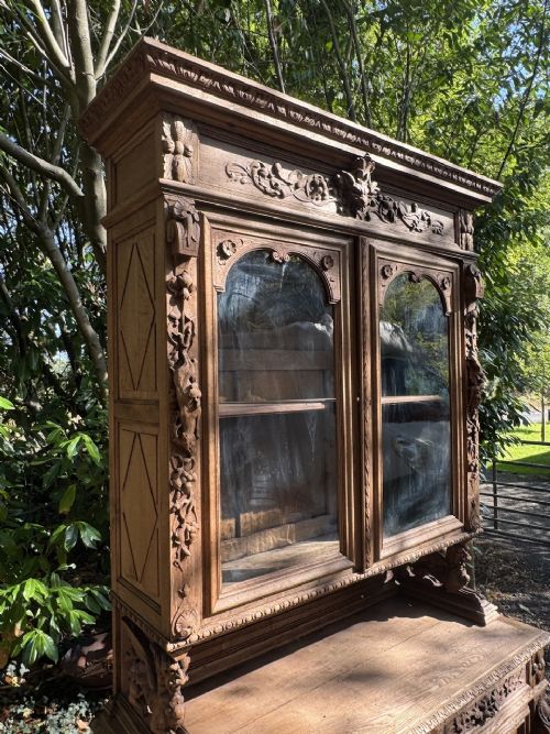 A two-piece bleached oak hunting cabinet featuring hand-carved relief panels of game birds, glazed upper doors, and a decorative mask pediment. View XIV