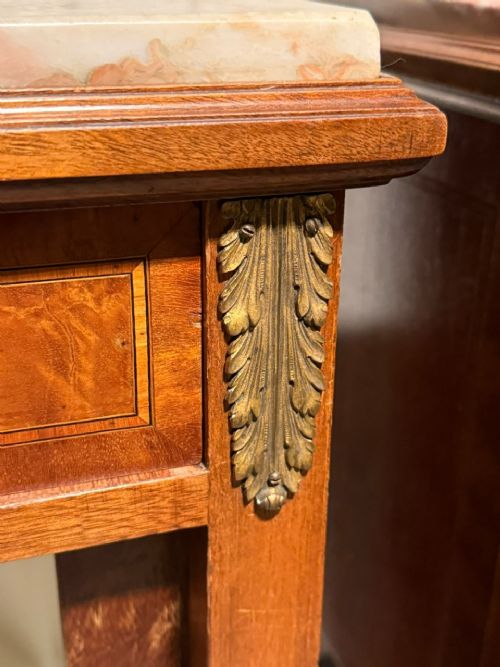 A pair of French Louis XVI style wooden bedside cabinets featuring marble tops, single drawers, inlaid cupboard doors, and gilt brass mounts on slender tapered legs. View V