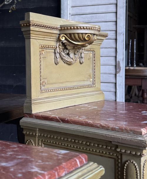 A matching pair of painted French neoclassical bedside cabinets featuring red marble tops, carved bracket superstructures, gold leaf detailing, drawers, and open lower shelves. View XII