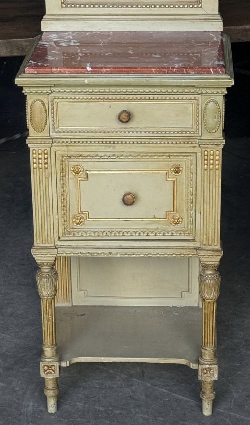 A matching pair of painted French neoclassical bedside cabinets featuring red marble tops, carved bracket superstructures, gold leaf detailing, drawers, and open lower shelves. View XIV
