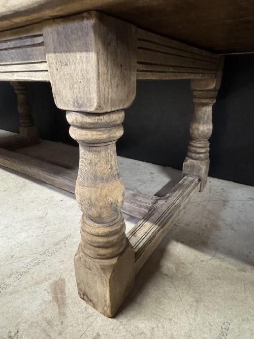 A large natural oak refectory dining table featuring turned legs, breadboard top ends, and an H-stretcher base. View XIII