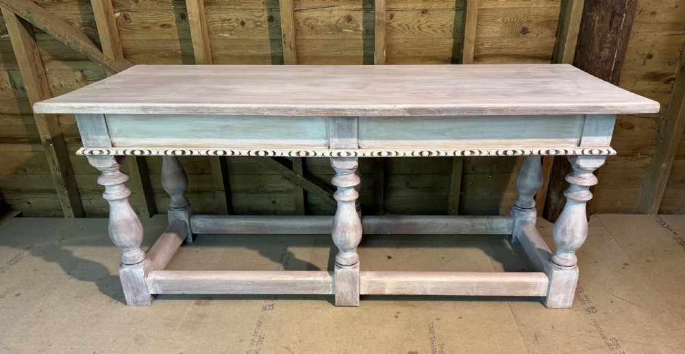 A nineteenth-century bleached oak console table featuring carved trim moulding under the frieze, six turned baluster legs, and a sturdy low stretcher base.