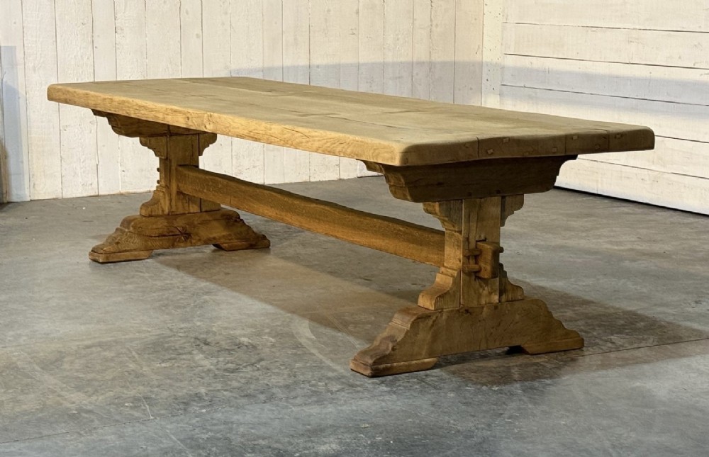 A large light oak farmhouse dining table featuring a solid plank top reinforced with butterfly joints and a sturdy trestle base connected by a central stretcher. View III