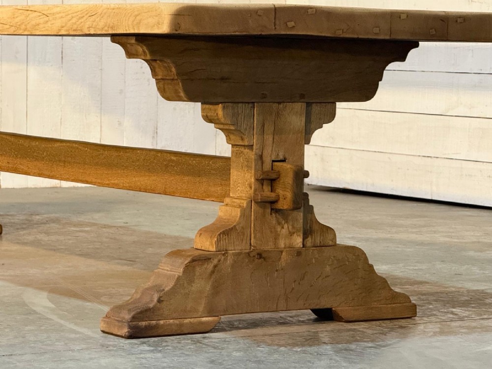 A large light oak farmhouse dining table featuring a solid plank top reinforced with butterfly joints and a sturdy trestle base connected by a central stretcher. View IV