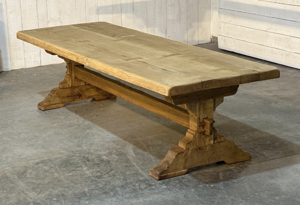 A large light oak farmhouse dining table featuring a solid plank top reinforced with butterfly joints and a sturdy trestle base connected by a central stretcher. View VI