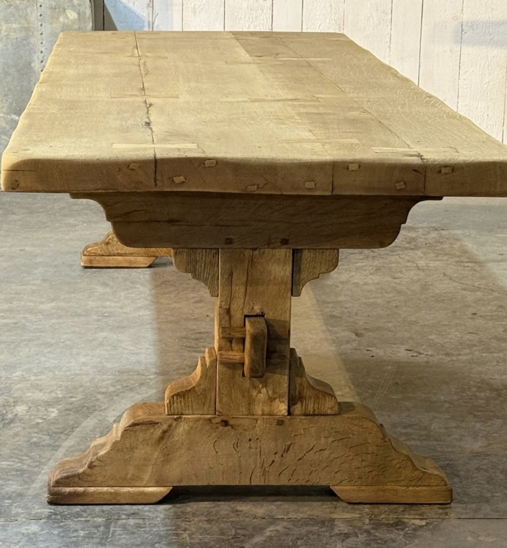 A large light oak farmhouse dining table featuring a solid plank top reinforced with butterfly joints and a sturdy trestle base connected by a central stretcher. View VII