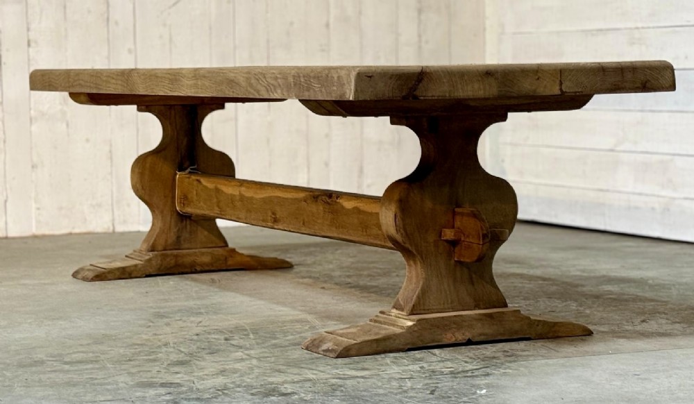 A large rustic French oak dining table featuring a thick timber plank top supported by a sturdy trestle base with a central keyed stretcher. View IV