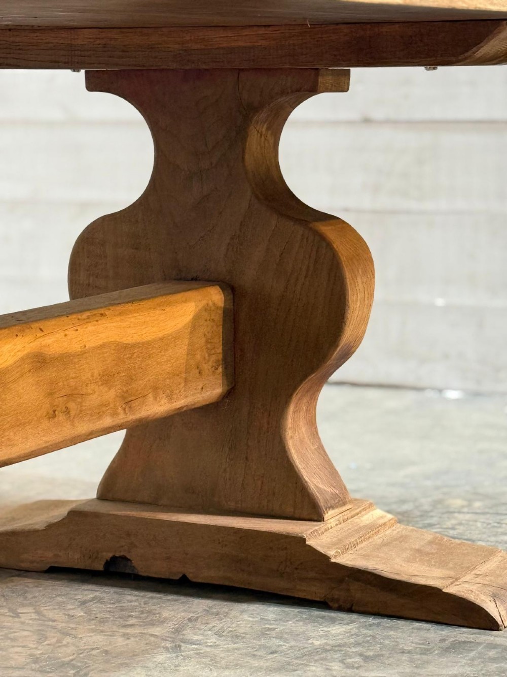 A large rustic French oak dining table featuring a thick timber plank top supported by a sturdy trestle base with a central keyed stretcher. View VII