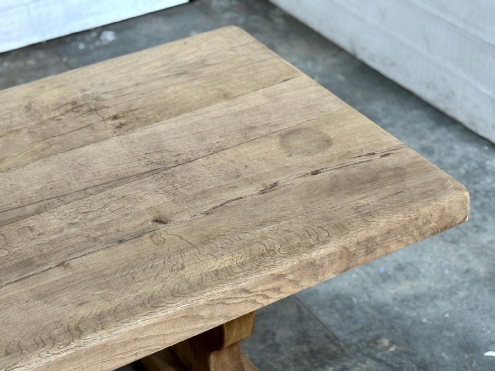 A large rustic French oak dining table featuring a thick timber plank top supported by a sturdy trestle base with a central keyed stretcher. View IX