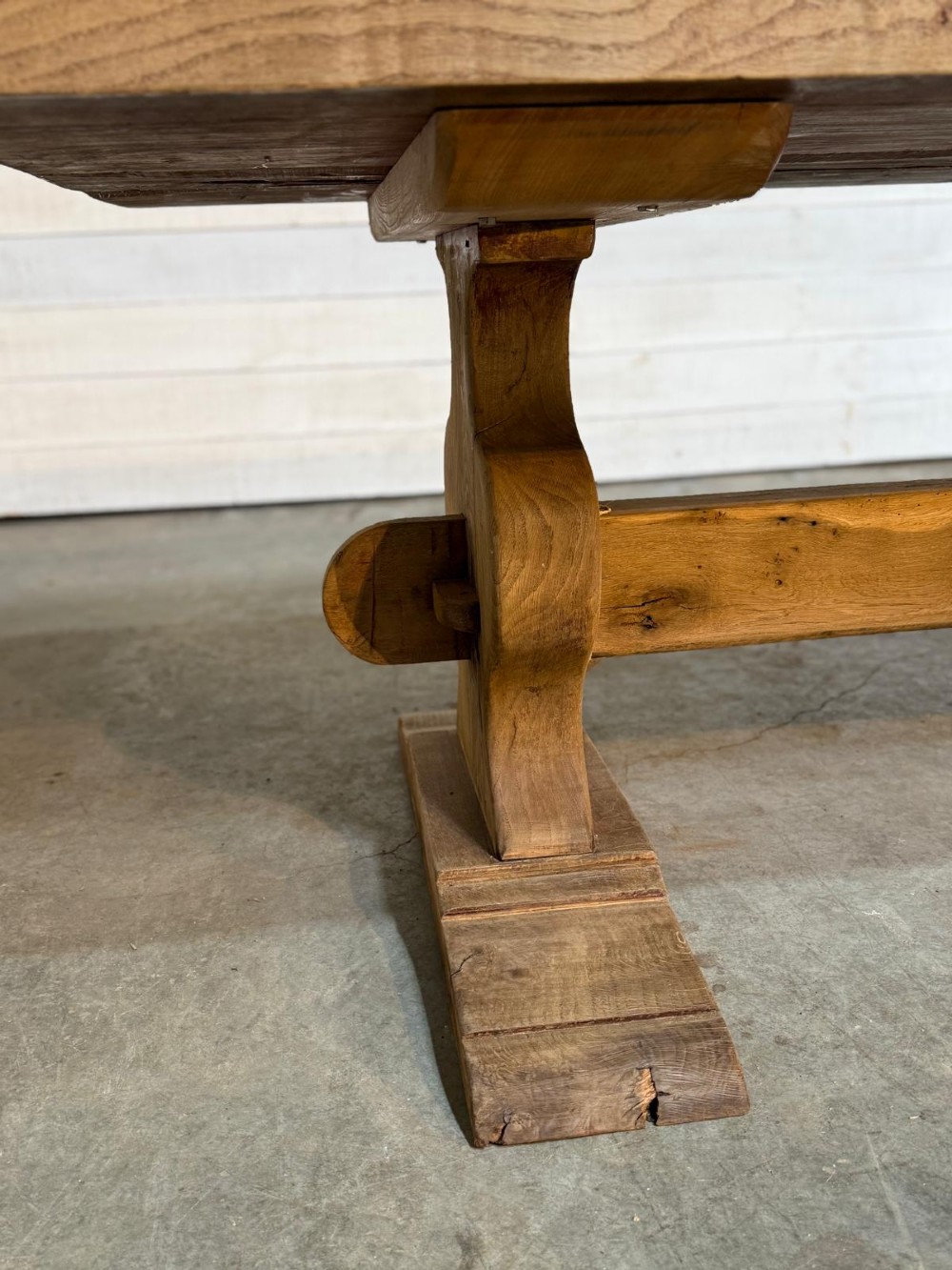 A large rustic French oak dining table featuring a thick timber plank top supported by a sturdy trestle base with a central keyed stretcher. View XV