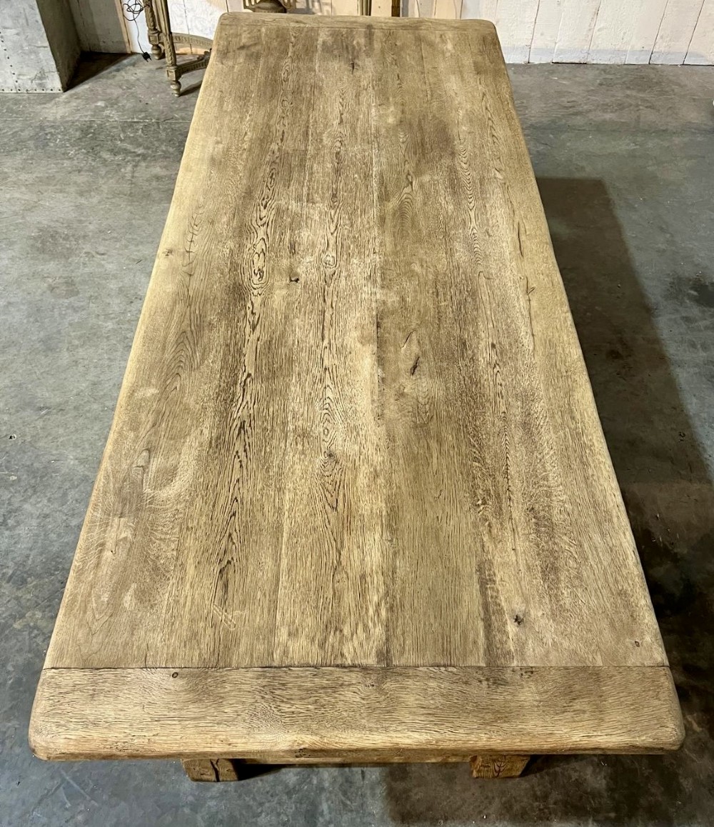 A rectangular bleached oak farmhouse dining table featuring turned legs, a low central stretcher, and a breadboard top. View II