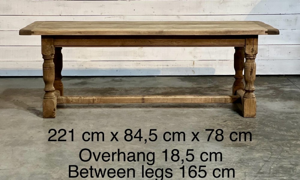 A rectangular bleached oak farmhouse dining table featuring turned legs, a low central stretcher, and a breadboard top. View III