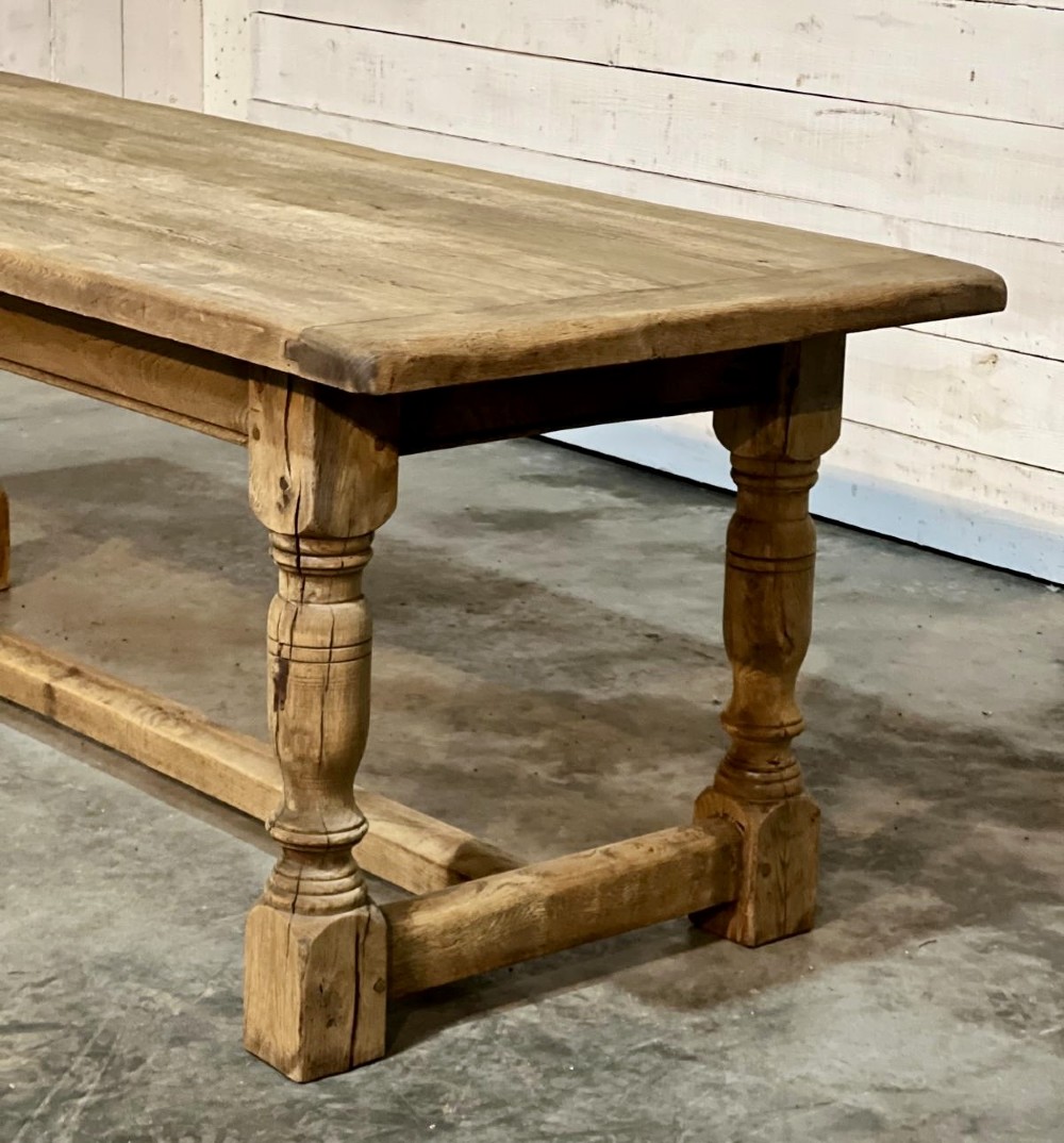 A rectangular bleached oak farmhouse dining table featuring turned legs, a low central stretcher, and a breadboard top. View IV