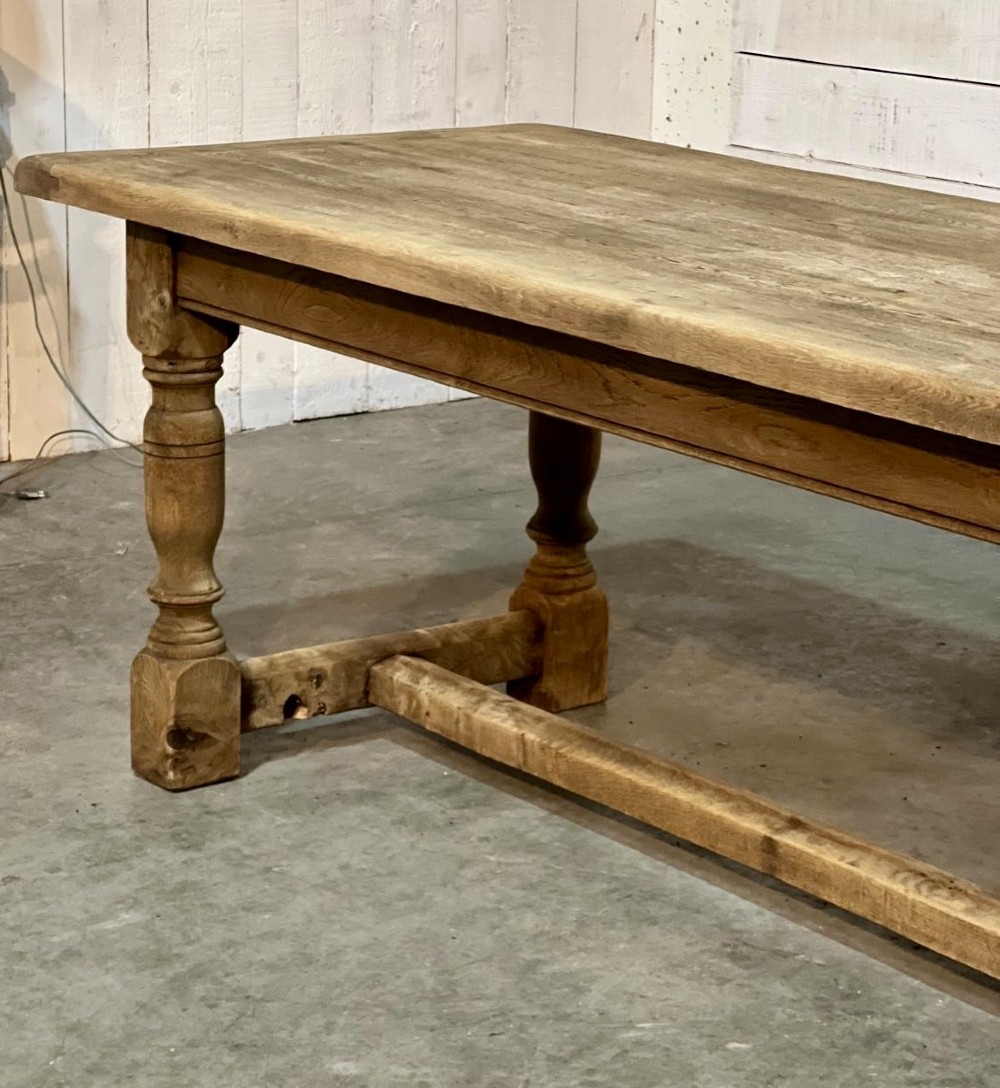 A rectangular bleached oak farmhouse dining table featuring turned legs, a low central stretcher, and a breadboard top. View V