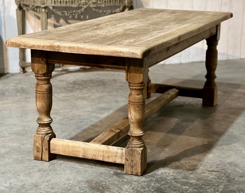 A rectangular bleached oak farmhouse dining table featuring turned legs, a low central stretcher, and a breadboard top. View VIII