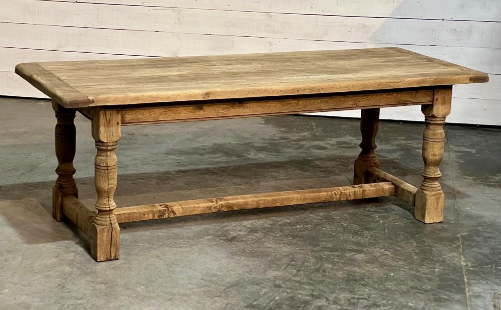 A rectangular bleached oak farmhouse dining table featuring turned legs, a low central stretcher, and a breadboard top. View IX