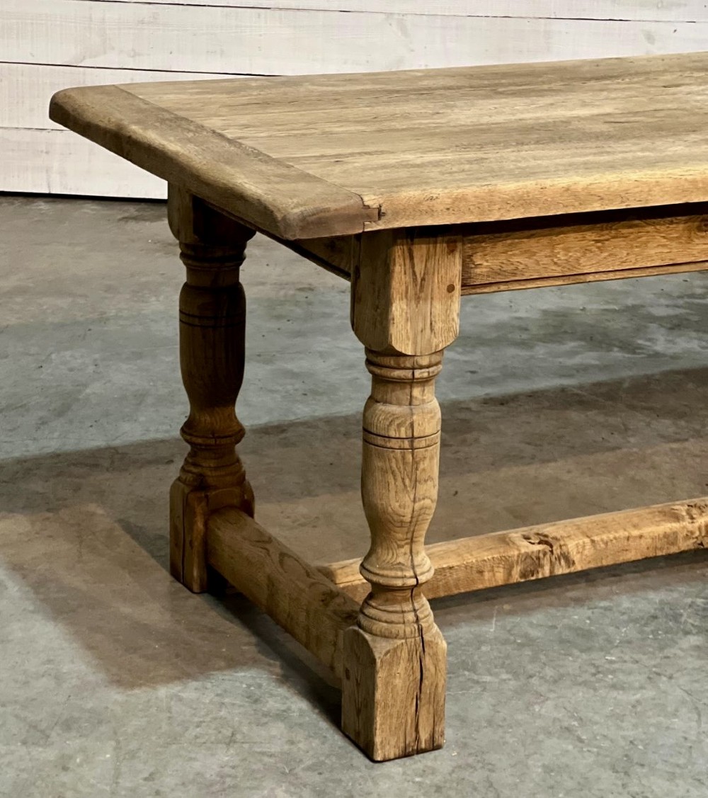 A rectangular bleached oak farmhouse dining table featuring turned legs, a low central stretcher, and a breadboard top. View XI