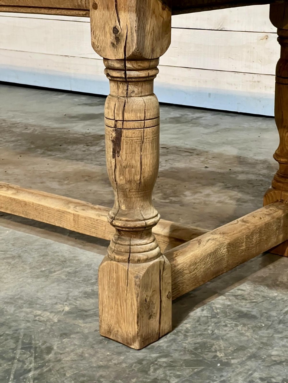 A rectangular bleached oak farmhouse dining table featuring turned legs, a low central stretcher, and a breadboard top. View XIV