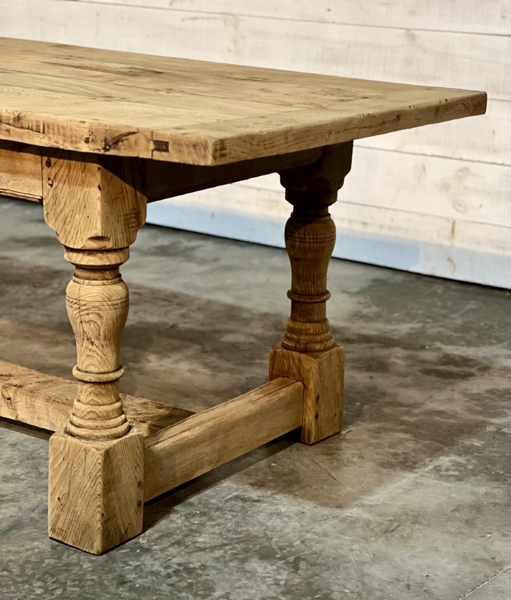 A rectangular bleached oak farmhouse dining table featuring turned baluster legs and a central stretcher base. View VII