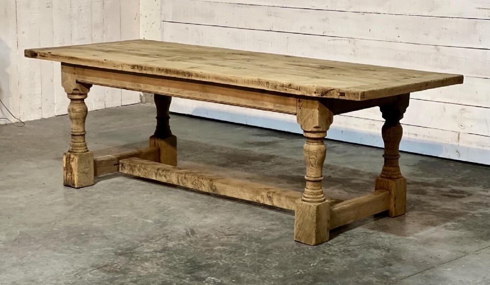 A rectangular bleached oak farmhouse dining table featuring turned baluster legs and a central stretcher base.