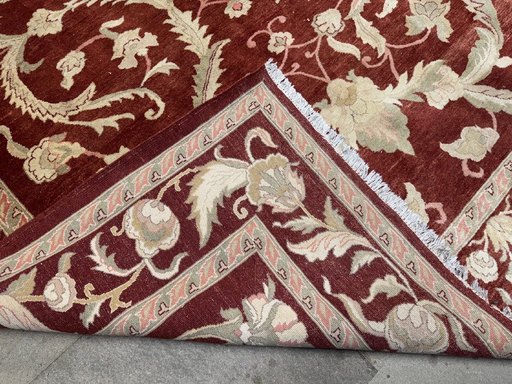 A large woven wool carpet featuring a deep red field decorated with cream and sage green floral scroll motifs and enclosed within a matching multi-tiered border. View III