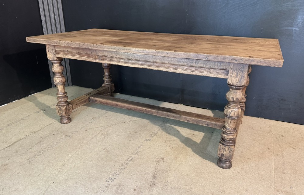 A solid oak farmhouse dining table with a thick plank top, turned baluster legs, and a low central stretcher rail. View II
