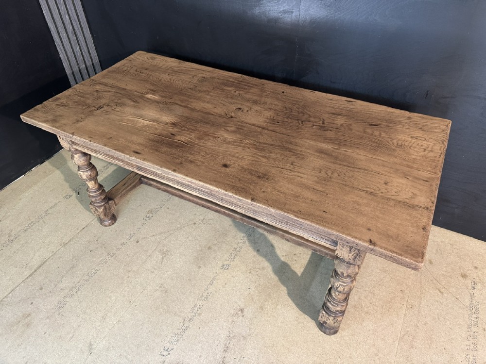 A solid oak farmhouse dining table with a thick plank top, turned baluster legs, and a low central stretcher rail. View III