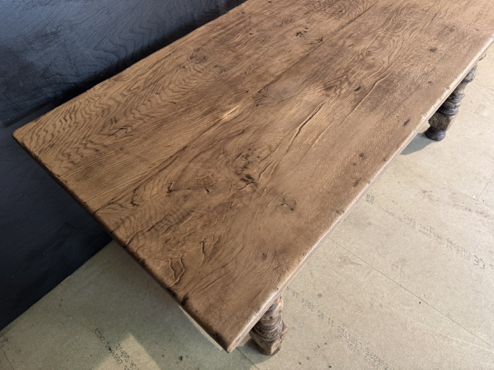 A solid oak farmhouse dining table with a thick plank top, turned baluster legs, and a low central stretcher rail. View V