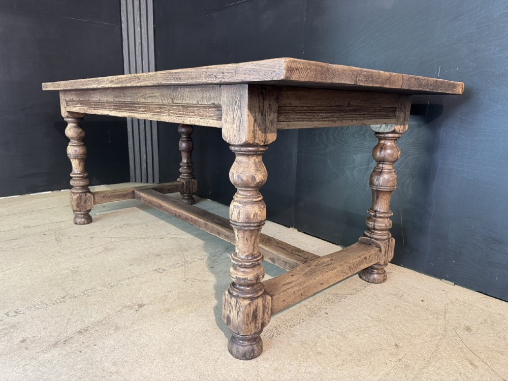 A solid oak farmhouse dining table with a thick plank top, turned baluster legs, and a low central stretcher rail. View IX
