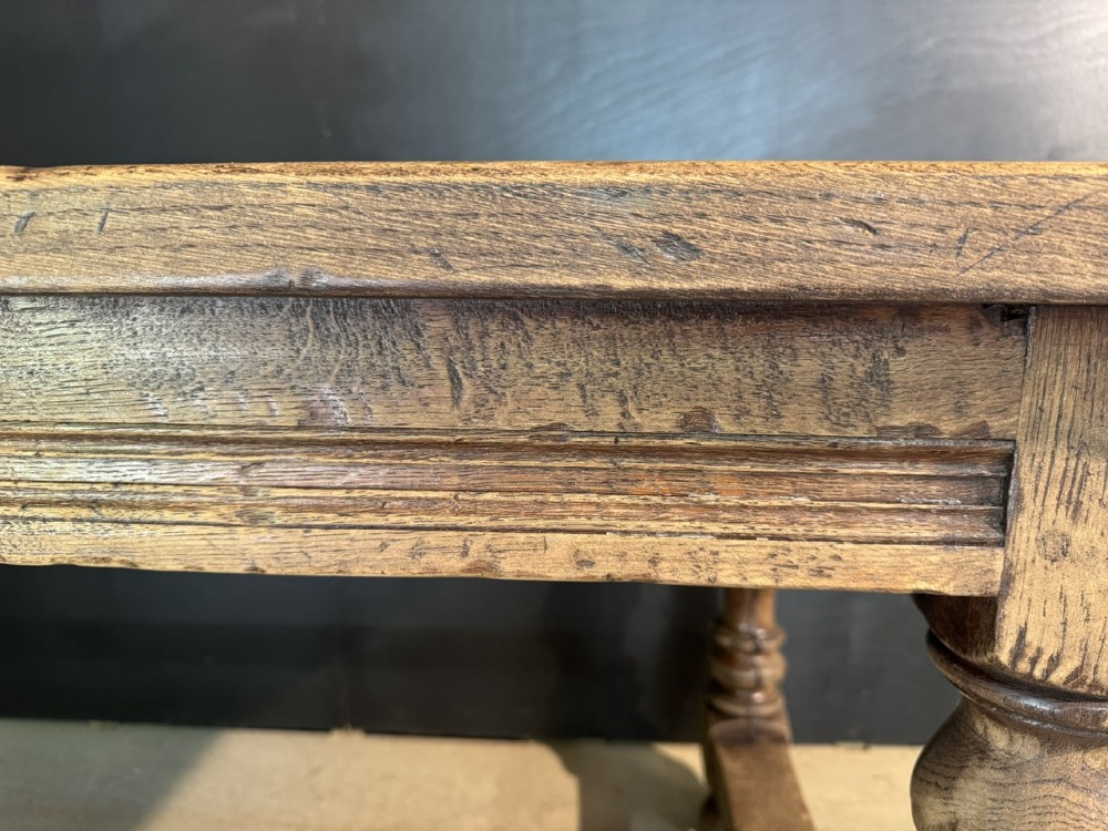 A solid oak farmhouse dining table with a thick plank top, turned baluster legs, and a low central stretcher rail. View XII