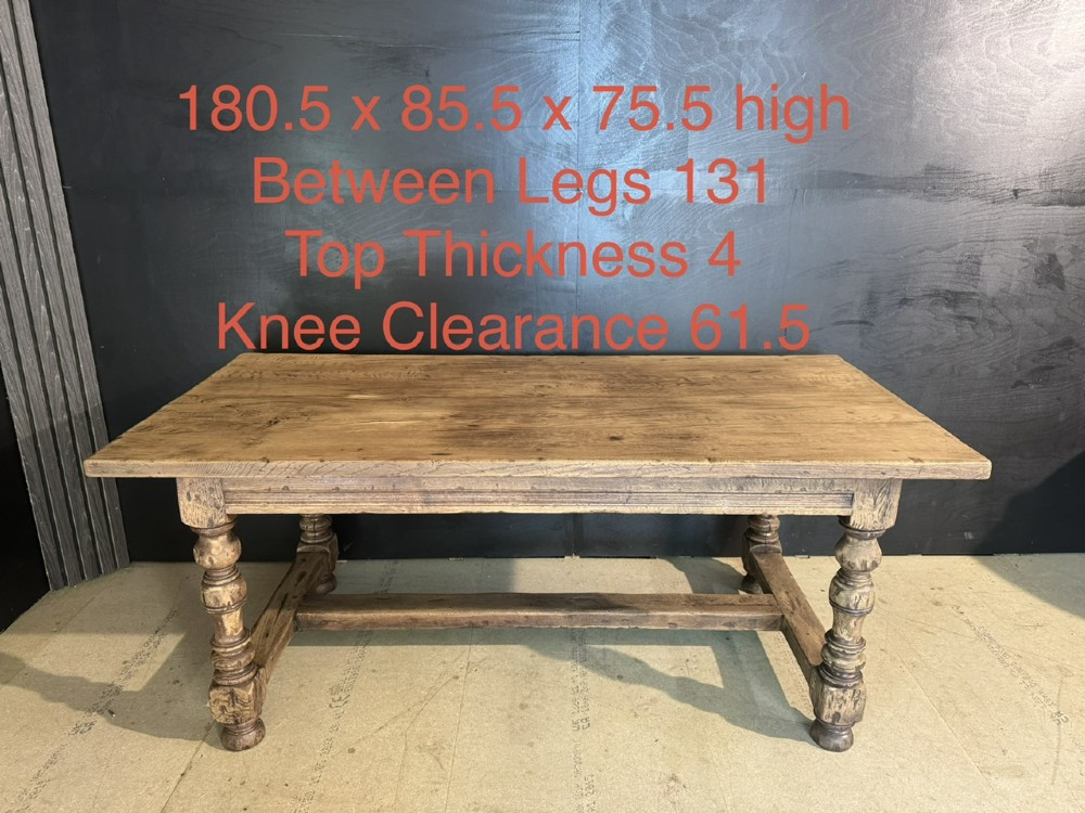 A solid oak farmhouse dining table with a thick plank top, turned baluster legs, and a low central stretcher rail. View XIV