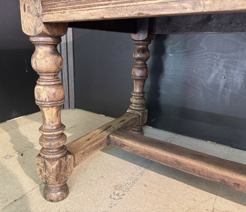 A solid oak farmhouse dining table with a thick plank top, turned baluster legs, and a low central stretcher rail. View XV