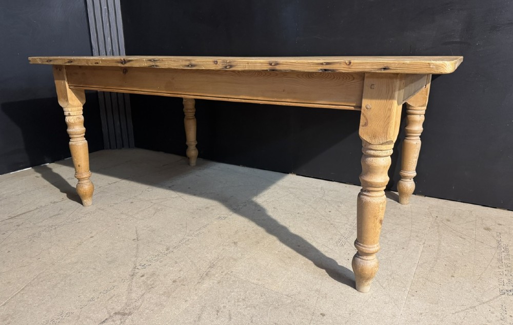 A rectangular pine farmhouse dining table featuring a solid plank top and four turned wooden legs. View III