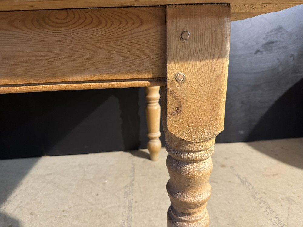 A rectangular pine farmhouse dining table featuring a solid plank top and four turned wooden legs. View X