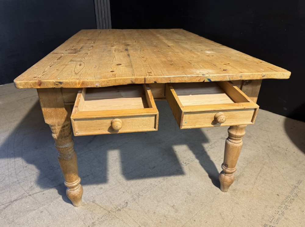 A rectangular pine farmhouse dining table featuring a solid plank top and four turned wooden legs. View XV