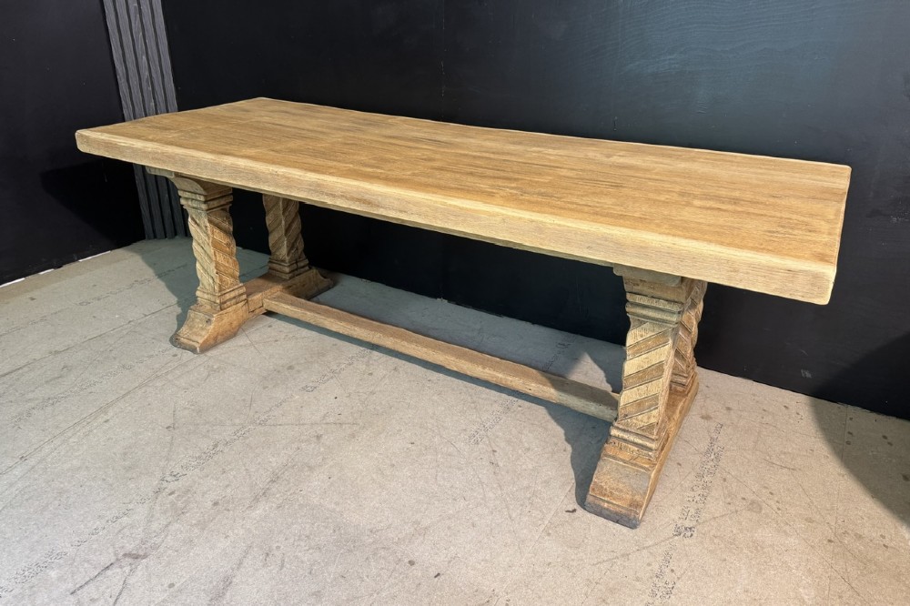 A large French rustic light oak dining table featuring a thick rectangular top supported by carved spiral trestle legs and a central stretcher.