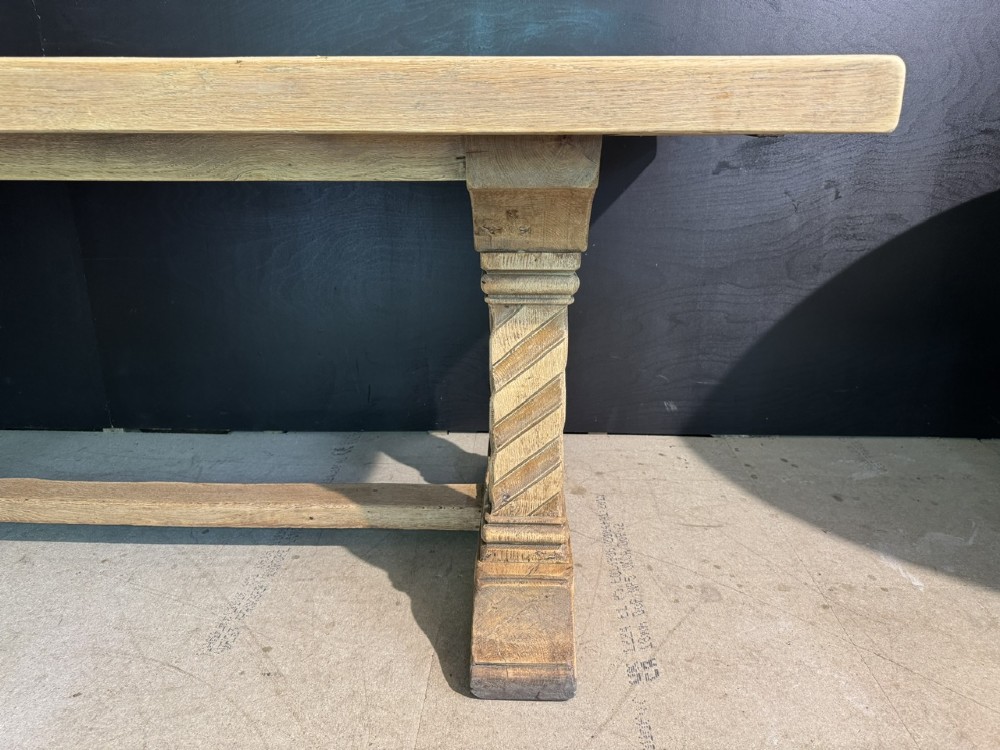 A large French rustic light oak dining table featuring a thick rectangular top supported by carved spiral trestle legs and a central stretcher. View VII