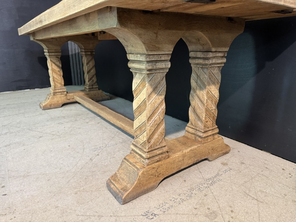 A large French rustic light oak dining table featuring a thick rectangular top supported by carved spiral trestle legs and a central stretcher. View IX