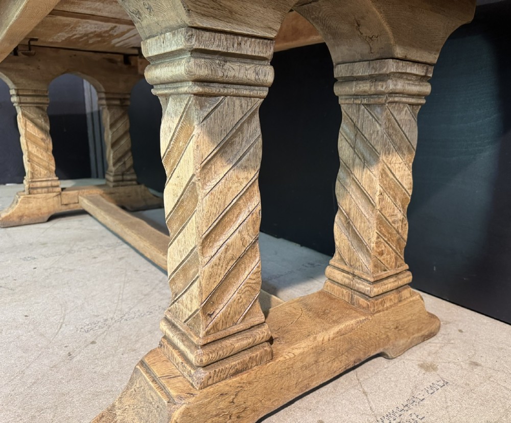 A large French rustic light oak dining table featuring a thick rectangular top supported by carved spiral trestle legs and a central stretcher. View X