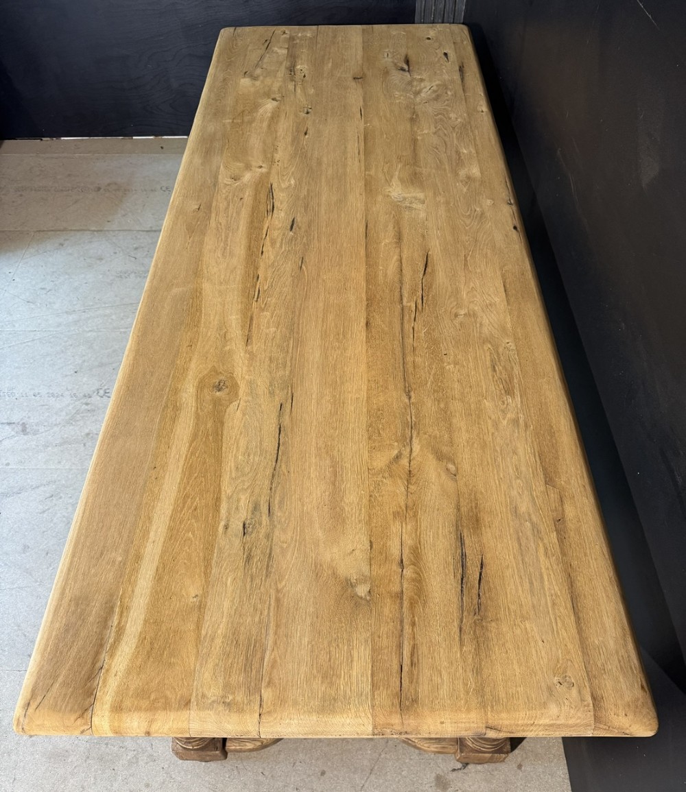 A long light oak French farmhouse table featuring a thick plank top, two frieze drawers, thick turned legs, and an H-stretcher base. View IV