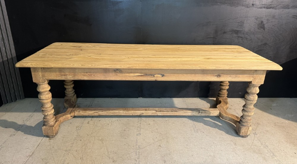 A long light oak French farmhouse table featuring a thick plank top, two frieze drawers, thick turned legs, and an H-stretcher base. View VI