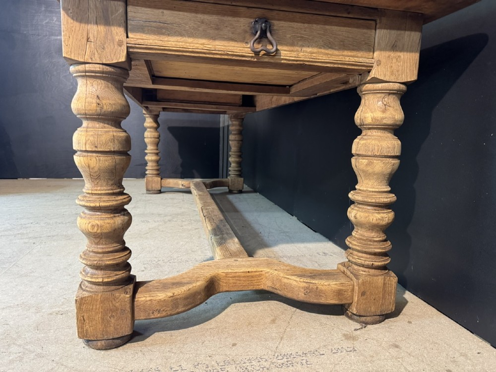 A long light oak French farmhouse table featuring a thick plank top, two frieze drawers, thick turned legs, and an H-stretcher base. View XI
