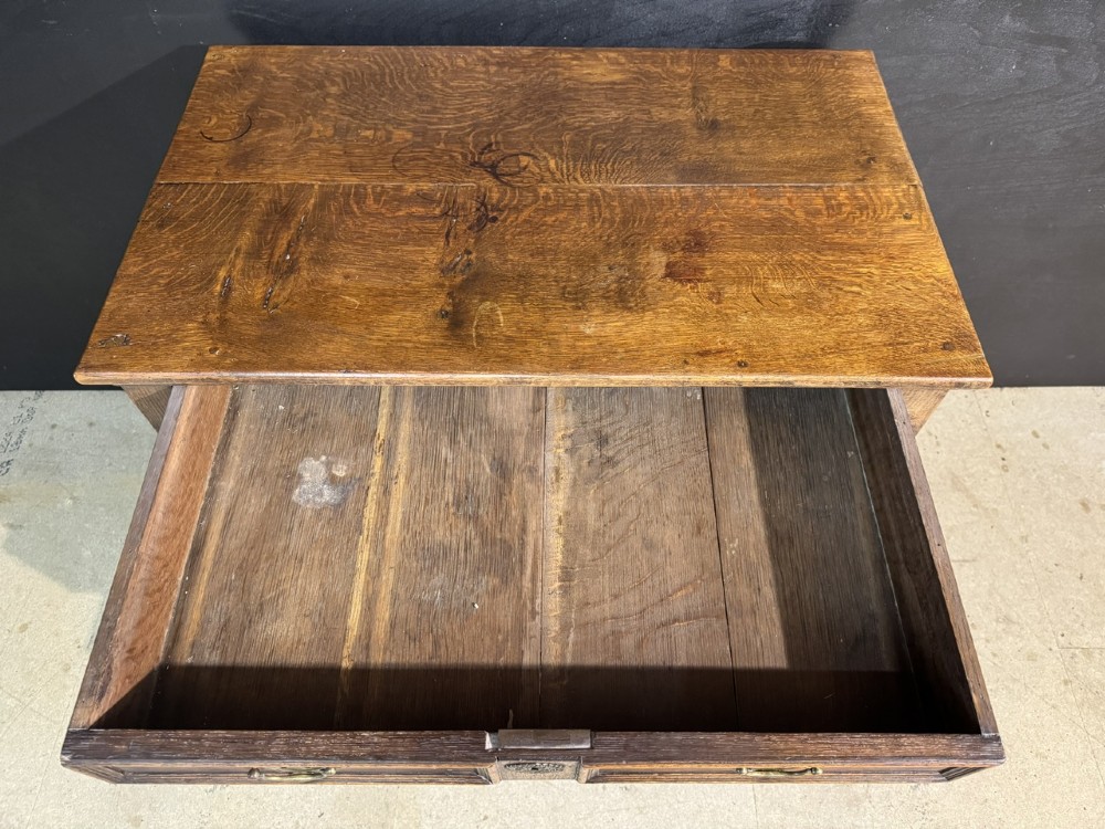 An eighteenth-century oak chest of drawers featuring geometric moulded drawer fronts, brass handles, and square block feet. View IX