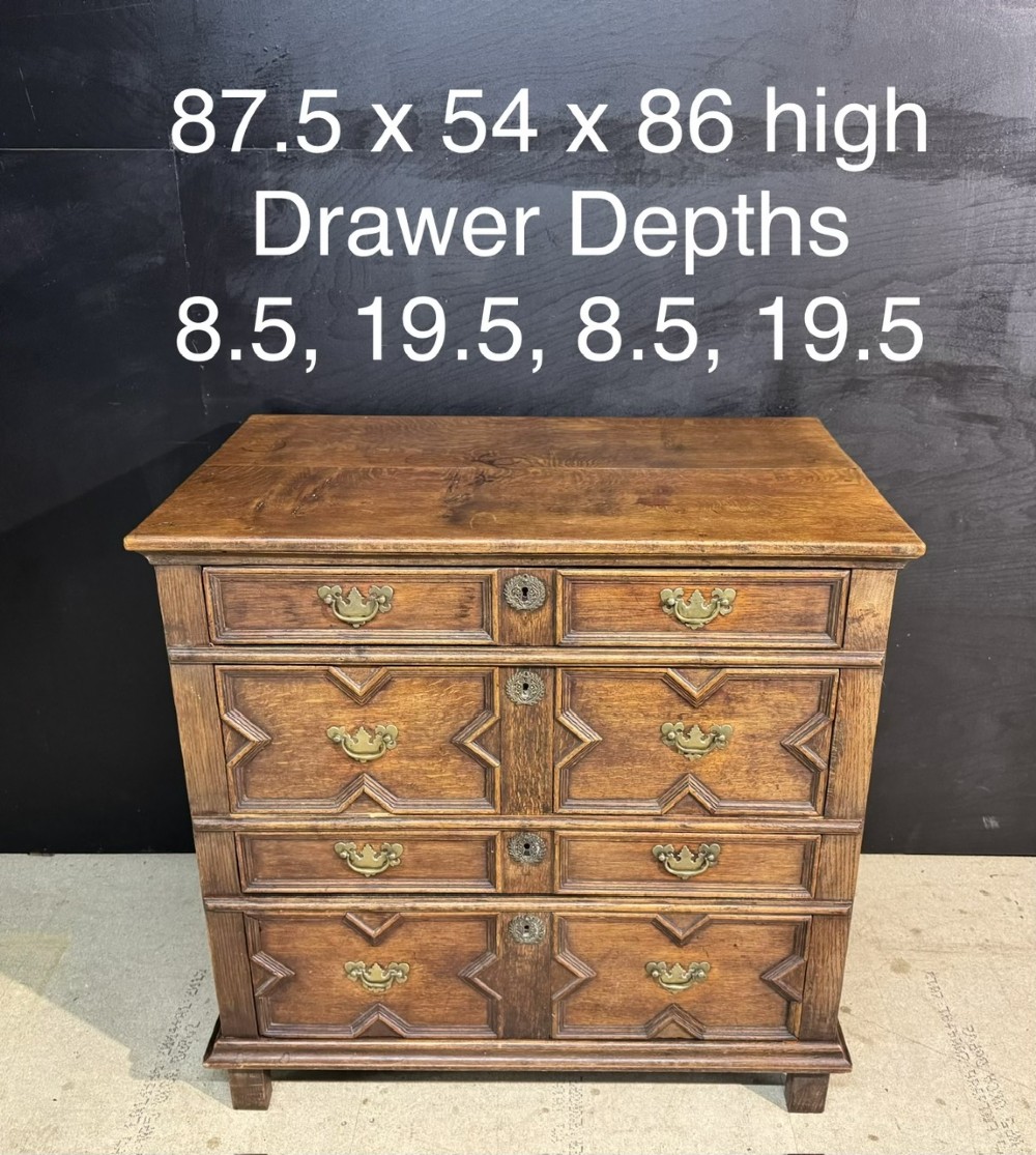 An eighteenth-century oak chest of drawers featuring geometric moulded drawer fronts, brass handles, and square block feet. View X