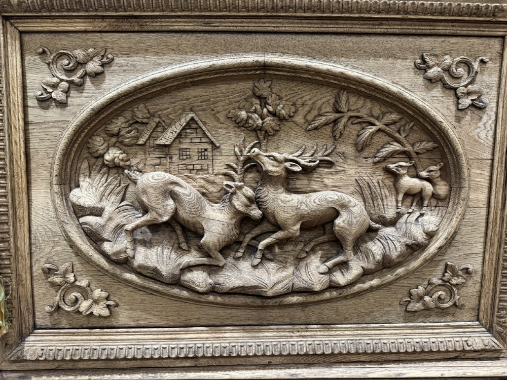 A light oak sideboard with detailed relief carvings of deer in a forest setting on the central panel, flanked by foliage motifs. View III