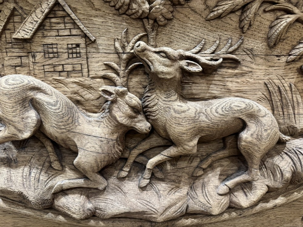 A light oak sideboard with detailed relief carvings of deer in a forest setting on the central panel, flanked by foliage motifs. View IV
