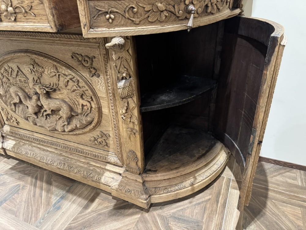 A light oak sideboard with detailed relief carvings of deer in a forest setting on the central panel, flanked by foliage motifs. View VIII